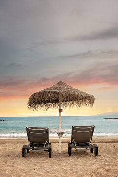 Lonely sunbeds and umbrella with view of stunning sunset - Tenerife, Canary Islands.