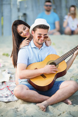 Young couple on the beach playing guitar