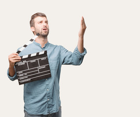 young handsome man holding a cinema clapper wearing a blue denim shirt . person isolated against...