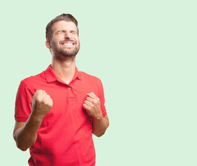 young handsome man celebrating a victory wearing a red polo shirt . person isolated against...
