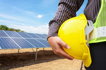 Young business man engineer hold yellow helmet at solar panel power plant construction site...
