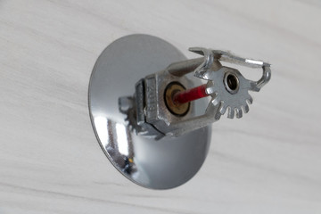 Automatic ceiling Fire Sprinkler on wall under ceiling. Sprinkler and smoke detector close up.