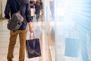 Closeup of male hand holding blue shopping bag in department store. Urban lifestyle in shopping mall concept