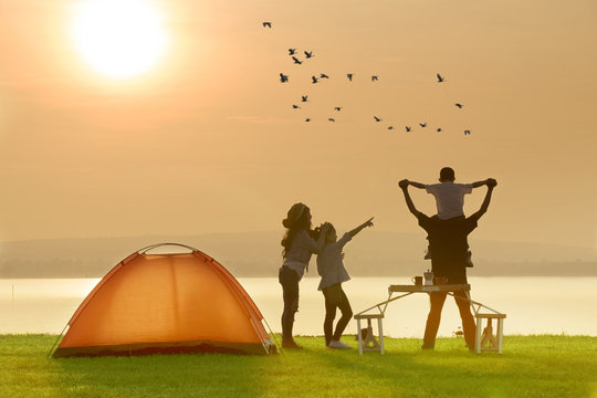 Happy family camping near the lake with sunset or sunrise background,happy family concept