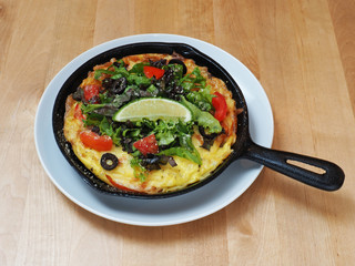 Classic Italian frittata with tomatoes and herbs in the pan