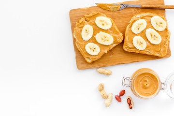 Sandwich with nut butter and banana for breakfast on white background top view copy space