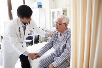 Fototapeta premium 医療用ベッドで医師の診断を受ける高齢者の男性。