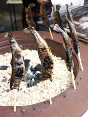 Ayu with salt being grilled outdoors in Japan.