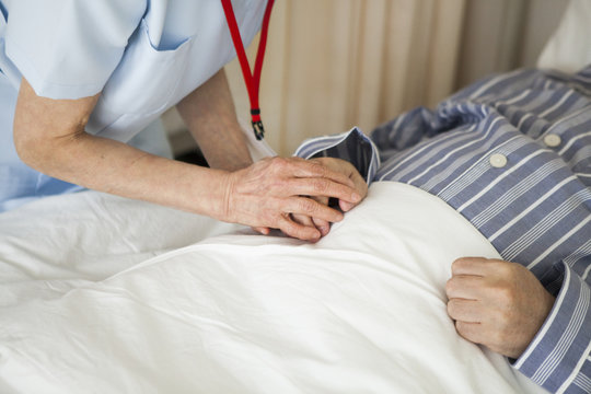 看護師が高齢者の患者の手を取り、励ましている。