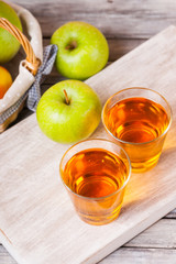 Apple juice in glasses and apples in a wicker basket on wooden table 