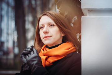 Portrait of a young woman in a black coat and red scarf in the city