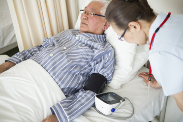 Obraz na płótnie Canvas 看護師に、血圧を測っている老人。
