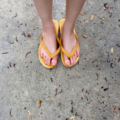 Yellow Sandals on Female Feet on Ground Background