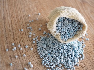 Old chemical fertilizer until the pellets start to break in the sack on the old wood board.