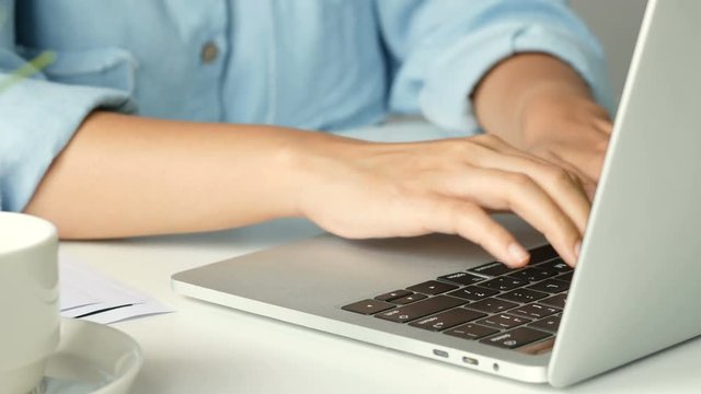 Close up hand typing on a Keyboard computer laptop at office. One young woman only using computer desktop PC.