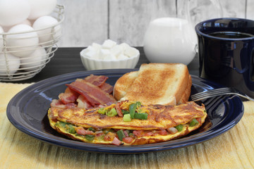 Western Omelet breakfast with toast and bacon.  Selective focus on omelet.