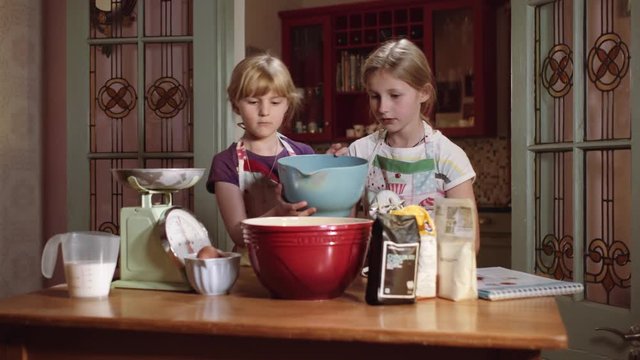 Children who could be Sisters Making a Chocolate Cake in the Kitchen from Scratch