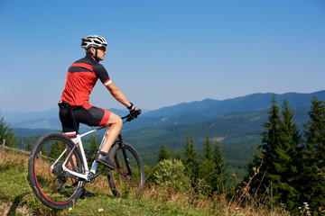 Young athletic professional tourist stopped on top of hill to enjoy beautiful view of distant...