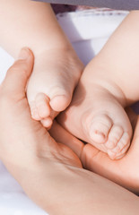 Fototapeta na wymiar Vertical view of baby feet in mother hands. Tiny newborn baby feet, concept of happy family.