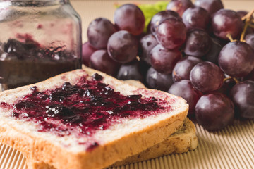 Whole wheat bread with grape jelly spread  on wooden table.