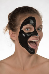 Happy beautiful girl smiling on a white background in a cosmetic mask black