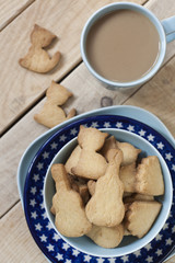 Delicious gingerbread cooked on a blue plate, a cup of coffee from milk to a light wooden background.
