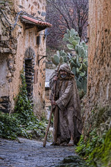 Man, dressed in rags, begging through the streets of a village