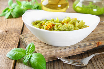 Pasta with pesto sauce on an old wooden table.