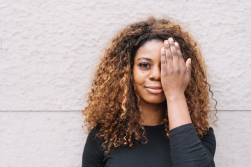 Pretty young African woman covering her eye