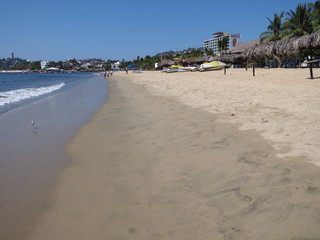 Scenery with umbrellas on sandy beach at bay of Acapulco city landscape in Mexico and waves of...