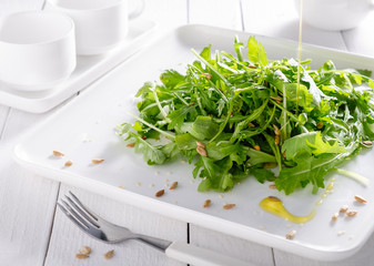 Eruca vesicaria fresh green lettuce dietary on white beautiful tableware.