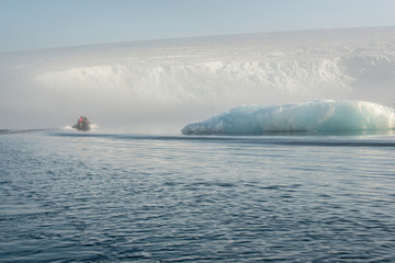 Inflatable boat with people in the waters of the Arctic ocean. Amid the icebergs and the glacier.