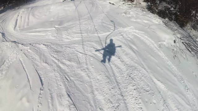 
4K.Shadow  in snow of Man skier  on ski lift in sunny day.
