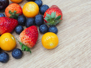 Fresh summer fruits, Cherry, strawberry, cape gooseberry and blueberry in wooden plate isolated on white background.