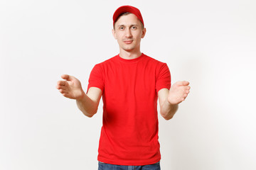 Fototapeta premium Delivery man in red uniform isolated on white background. Professional male in cap, t-shirt working as courier or dealer holding virtual object. Spreading hands gesture. Copy space for advertisement.