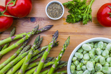 Fresh seasonal green vegetables asparagus and broad bean with tomatoes.