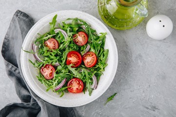 Green salad arugula with tomatoes and red onion in bowl