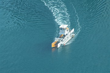 Anti pollution boat working on a coast line  in Dubai and collecting all floating objects. Ocean cleaning, plastic collection.