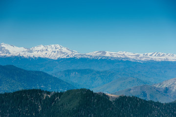 Fototapeta na wymiar Amazing views in the Caucasus mountains. Snow-capped peaks, blue sky, sunny day