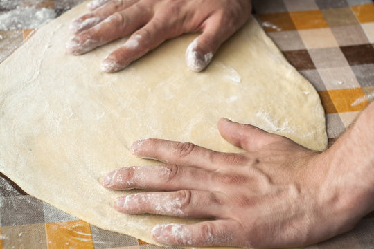 Cooking and home concept - close up of male hands kneading dough on a background in cell