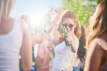 Ginger girl dancing, drinking an having a good time at outdoor party 