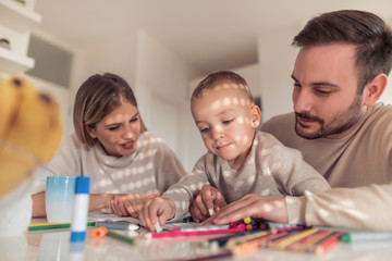 Obraz na płótnie Canvas Mom and dad drawing with their son