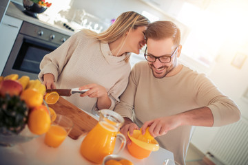 Happy couple making fresh orange juice