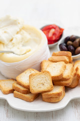 toasts with cheese, olives and red pepper on white dish