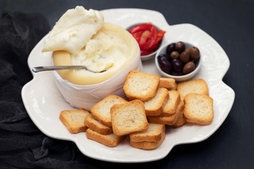 toasts with cheese, olives and red pepper on white dish