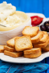 toasts with cheese, olives and red pepper on white dish