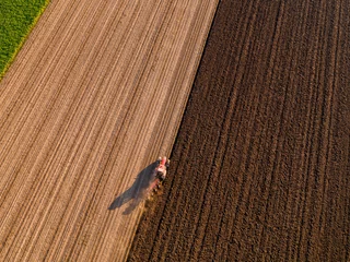 Fotobehang Aerial shot of a farmer plowing stubble field © oticki