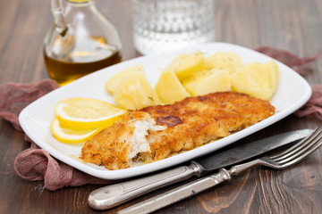 fried fillet of fish with boiled potato on white dish