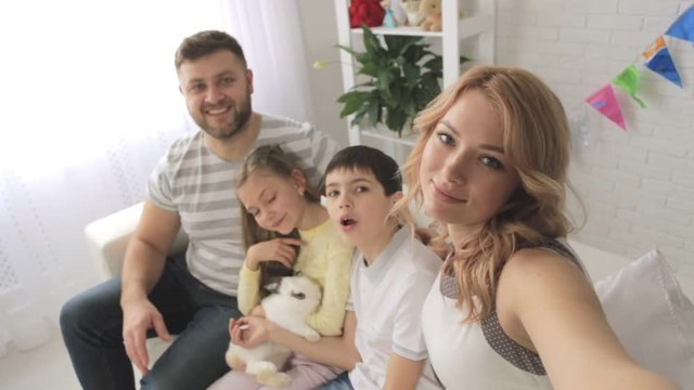 Happy family with two children and rabbit taking selfies. Shooting first-person