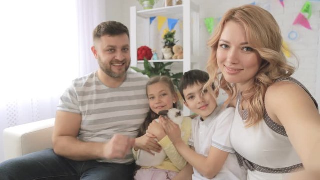 Cheerful family with two children and rabbit taking selfies. Shooting first-person